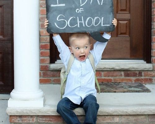 Little kid holding up a first day of school sign