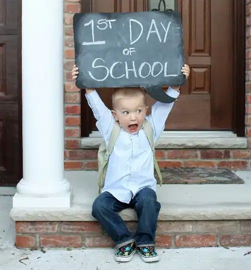 Little kid holding up a first day of school sign